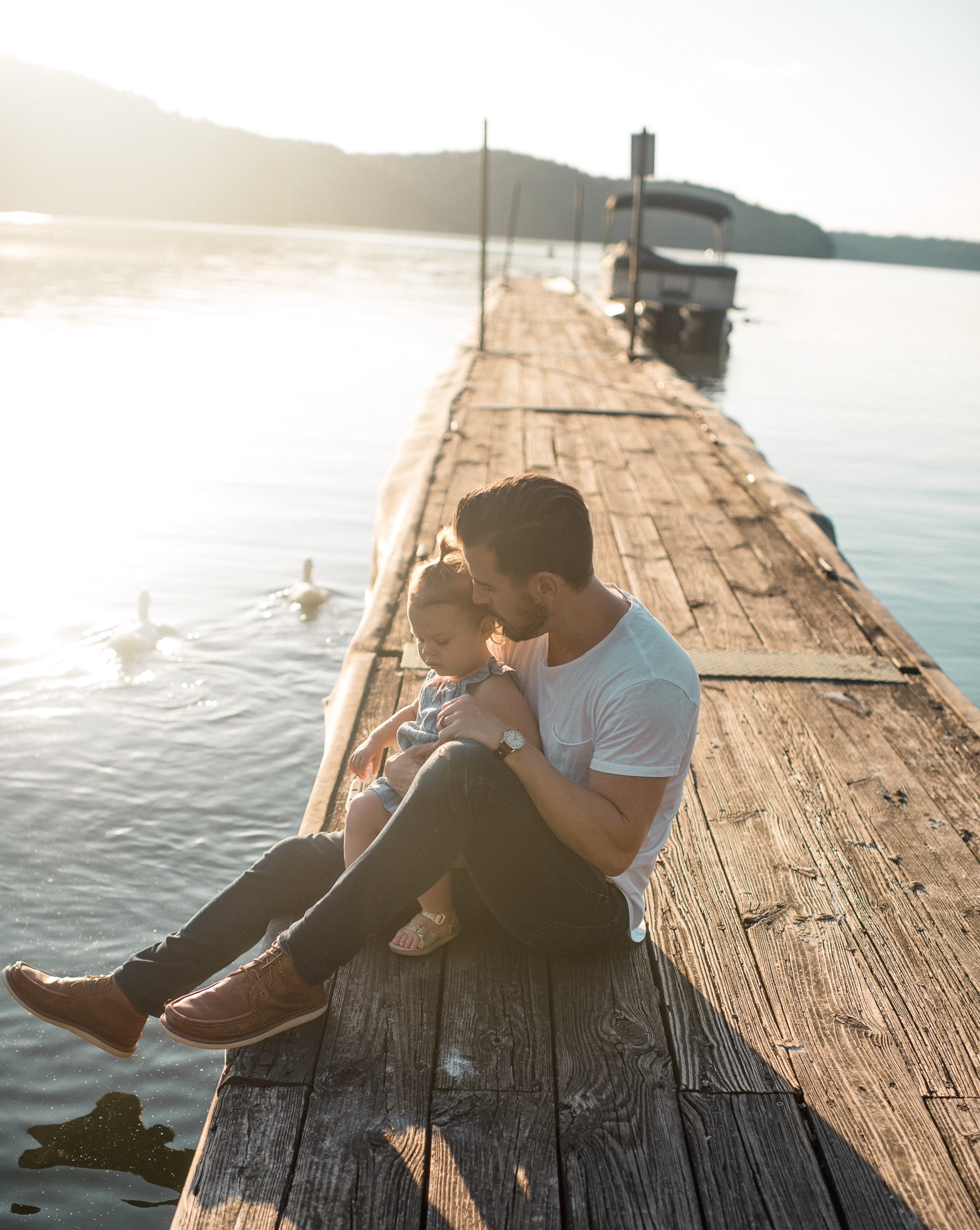 dad and baby sitting on a dock